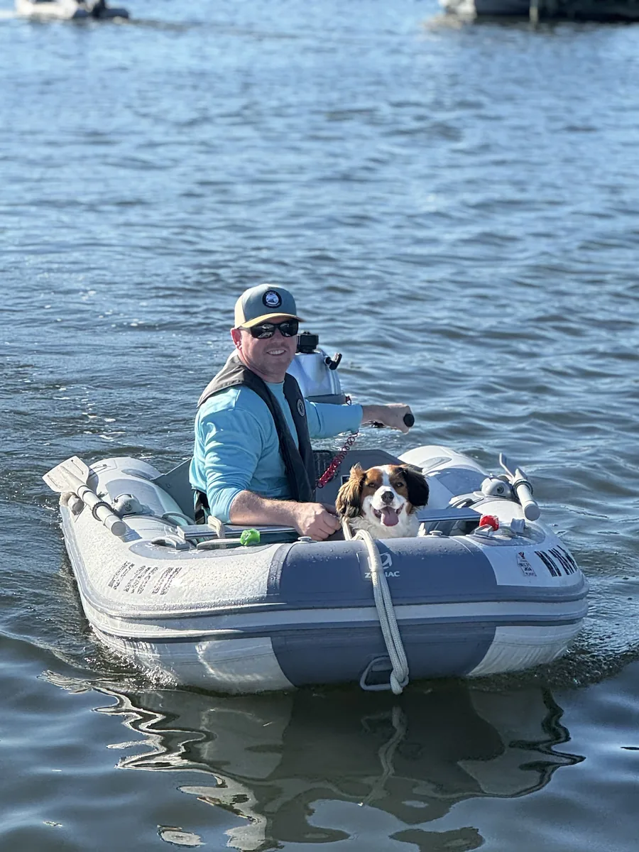 Donny Morrell driving an inflatable tender on the water with his dog